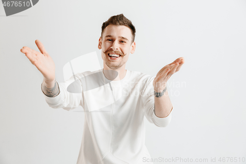 Image of The happy businessman standing and smiling against gray background.