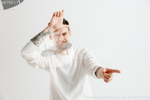 Image of Losers go home. Portrait of happy guy showing loser sign over forehead