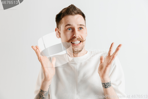 Image of The young attractive man looking suprised isolated on gray