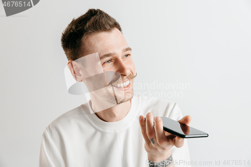 Image of Indoor portrait of attractive young man holding smartphone