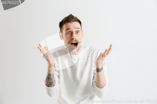 Image of The young attractive man looking suprised isolated on gray