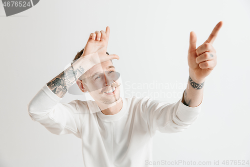 Image of Losers go home. Portrait of happy guy showing loser sign over forehead