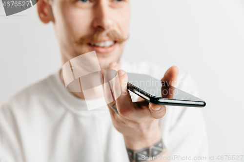 Image of Indoor portrait of attractive young man holding smartphone