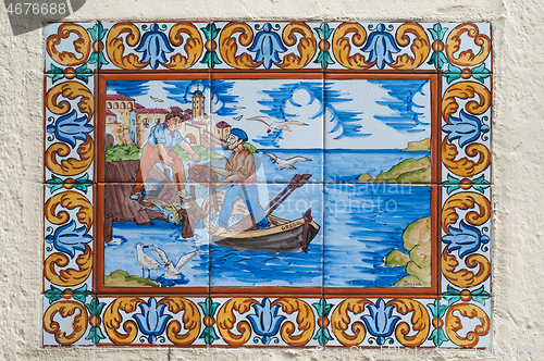 Image of BARCELONA, SPAIN - JUNE 2, 2013: Picture of a mosaic depicting the fisher in Spain. An image of specially painted tiles and pieces of glaze on the wall of a house in Barcelona