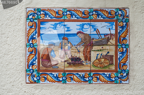 Image of BARCELONA, SPAIN - JUNE 2, 2013: Picture of a mosaic depicting the fisher in Spain. An image of specially painted tiles and pieces of glaze on the wall of a house in Barcelona