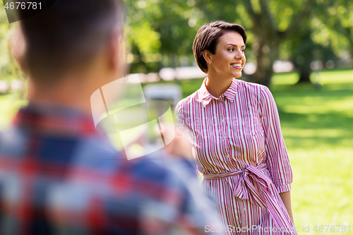 Image of couple photographing by smartphone in park