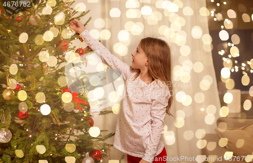 Image of happy girl in red dress decorating christmas tree