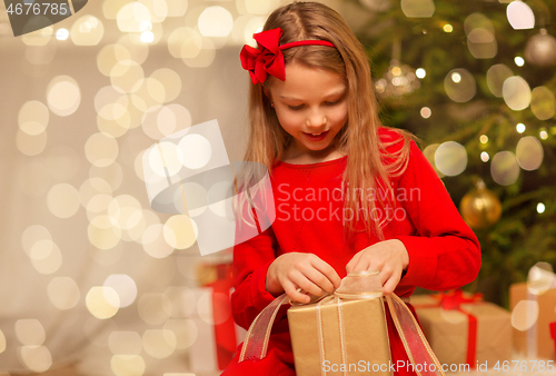 Image of smiling girl with christmas gift at home