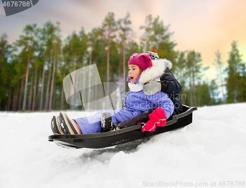 Image of little kids sliding on sled down hill in winter