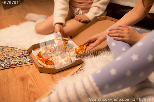 Image of happy female friends eating pizza at home