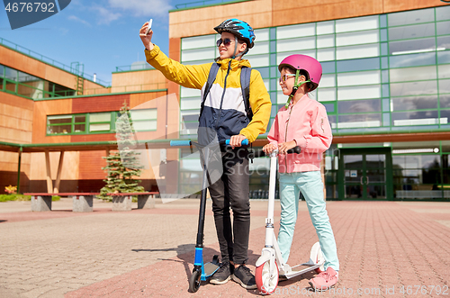 Image of happy school kids with scooters taking selfie