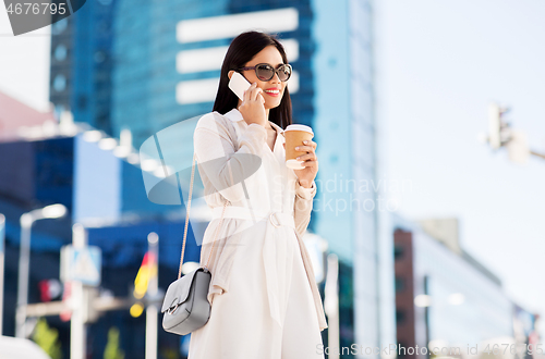 Image of smiling asian woman calling on smartphone in city