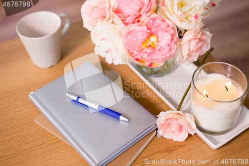 Image of burning candle and flower bunch on wooden table