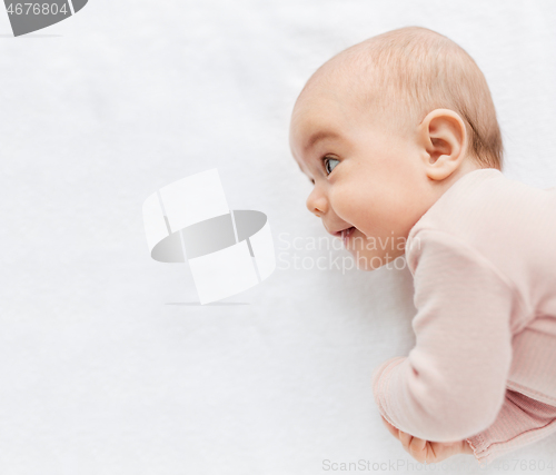 Image of sweet baby girl lying on white blanket