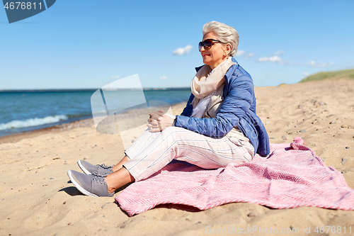 Image of happy senior woman in jacket on beach