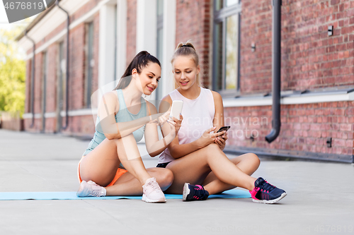 Image of sporty women or friends with smartphone on rooftop