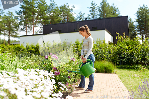 Image of young woman watering flowers at garden