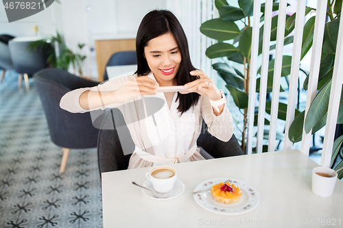 Image of woman photographing coffee by smartphone at cafe