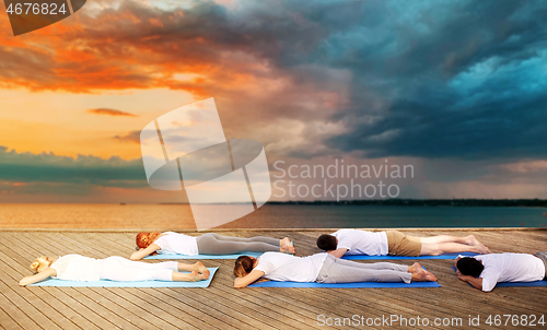 Image of group of people making yoga exercises outdoors