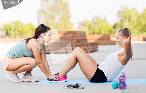 Image of women training and doing sit-ups outdoors