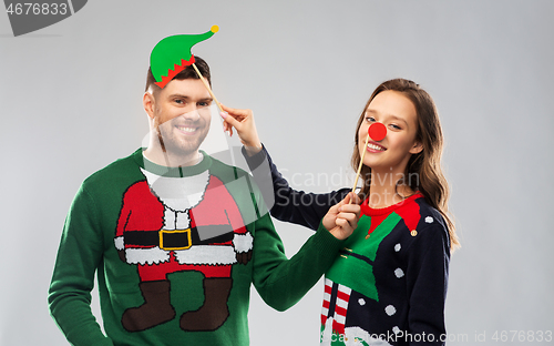 Image of couple with christmas party props in ugly sweaters