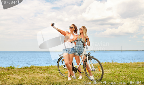 Image of teenage girls with bicycle taking selfie in summer