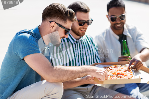 Image of male friends eating pizza with beer on street