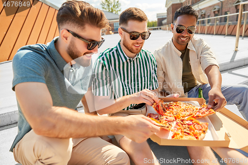 Image of male friends eating pizza with beer on rooftop