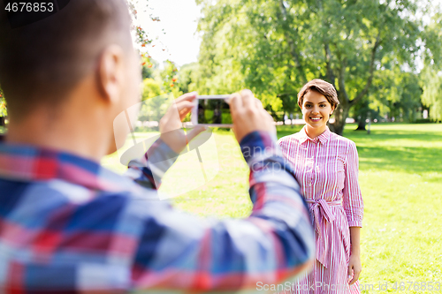 Image of couple photographing by smartphone in park
