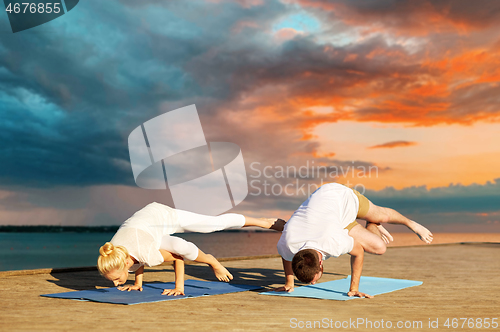 Image of couple making yoga side crane pose outdoors