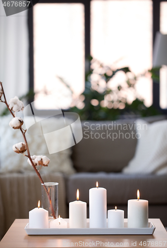 Image of burning white candles on table at cozy home