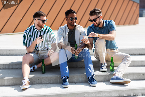 Image of men with smartphones drinking beer on street