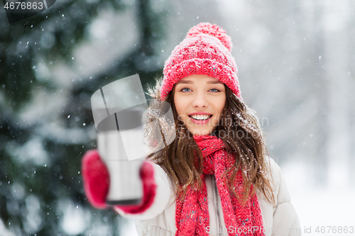 Image of young woman with hot drink in tumbler in winter