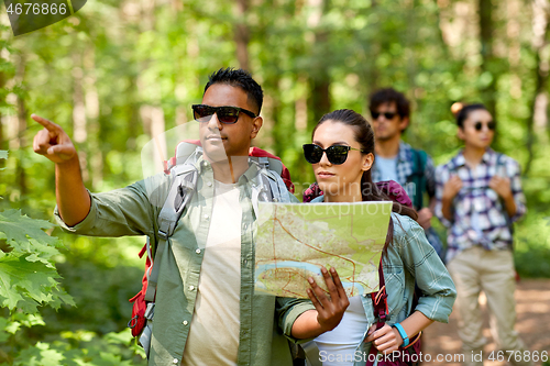 Image of friends with map and backpacks hiking in forest