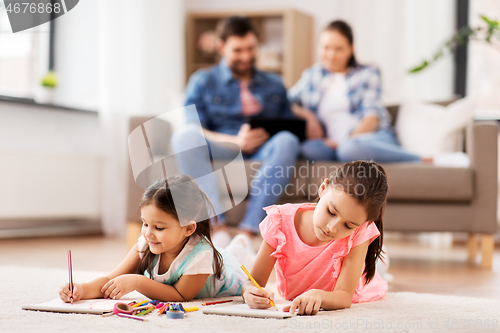 Image of happy sisters drawing in sketchbooks at home