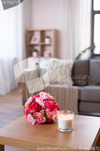 Image of burning fragrance candle and flower bunch at home
