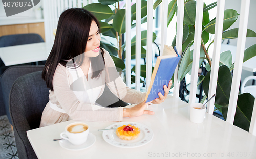 Image of woman drinking coffee and reading book at cafe