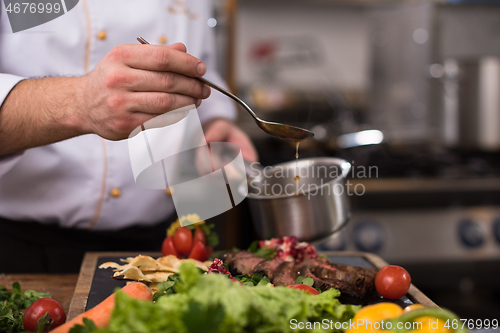 Image of Chef hand finishing steak meat plate