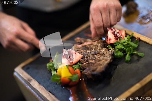 Image of closeup of Chef hands serving beef steak