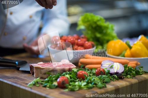 Image of Chef putting salt on juicy slice of raw steak