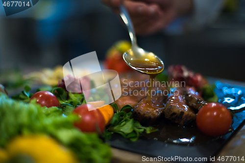 Image of Chef hand finishing steak meat plate