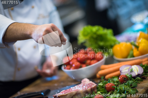 Image of Chef putting salt on juicy slice of raw steak