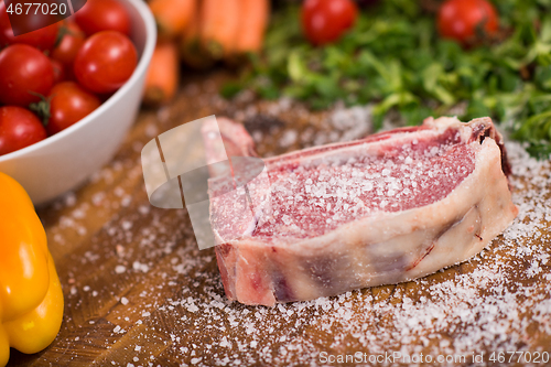 Image of Juicy slice of raw steak on wooden table