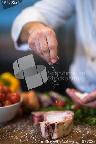 Image of Chef putting salt on juicy slice of raw steak