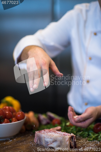 Image of Chef putting salt on juicy slice of raw steak