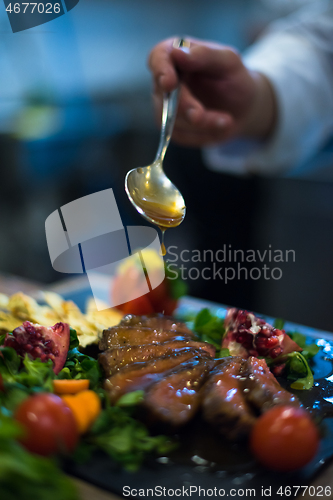 Image of Chef hand finishing steak meat plate