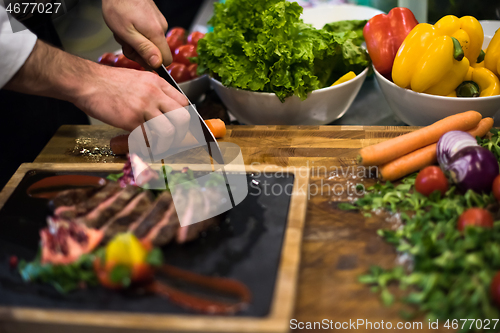 Image of closeup of Chef hands serving beef steak