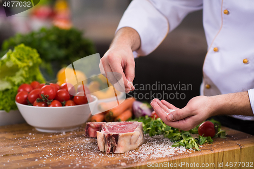 Image of Chef putting salt on juicy slice of raw steak