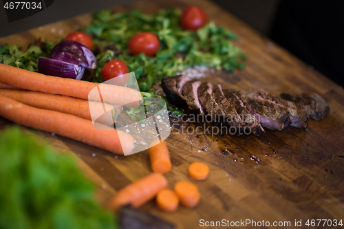Image of Juicy slices of grilled steak on wooden board