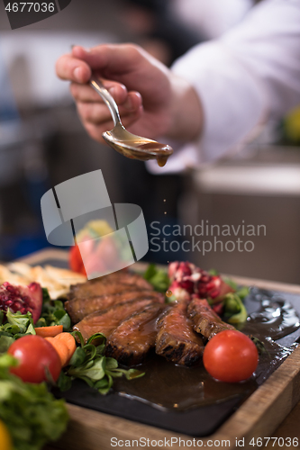 Image of Chef hand finishing steak meat plate